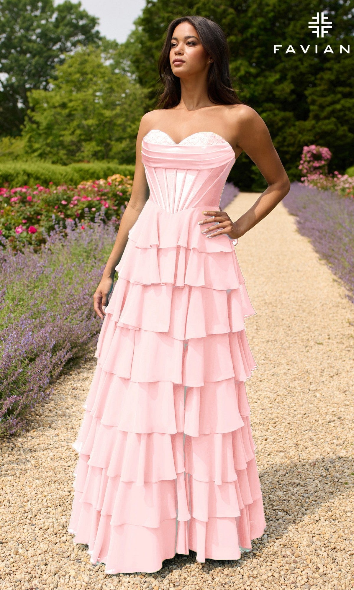 A woman stands on a garden path in the Strapless Long Ruffled Prom Gown: Faviana 11436, light pink with a fitted bodice. The FAVIAN logo appears in the upper right corner.